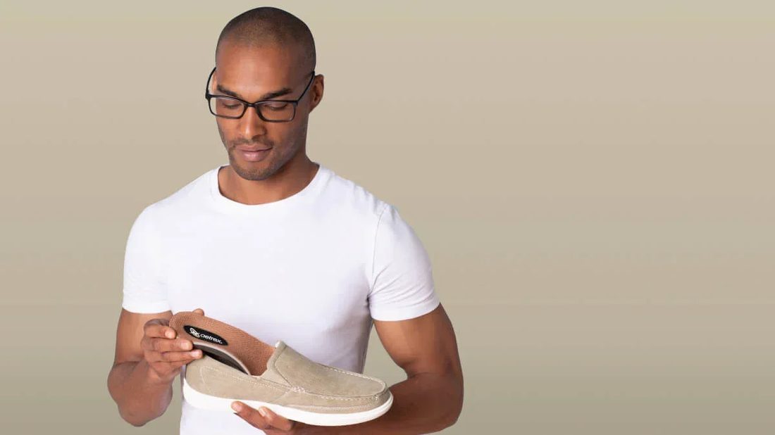 A person placing an Aetrex insole into an everyday shoe